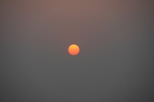 A striking orange sun setting over Dhaka, creating a serene and minimalist atmosphere.