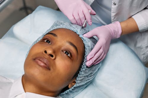 Free Dermatologist Injecting Botox on Client's Forehead Stock Photo