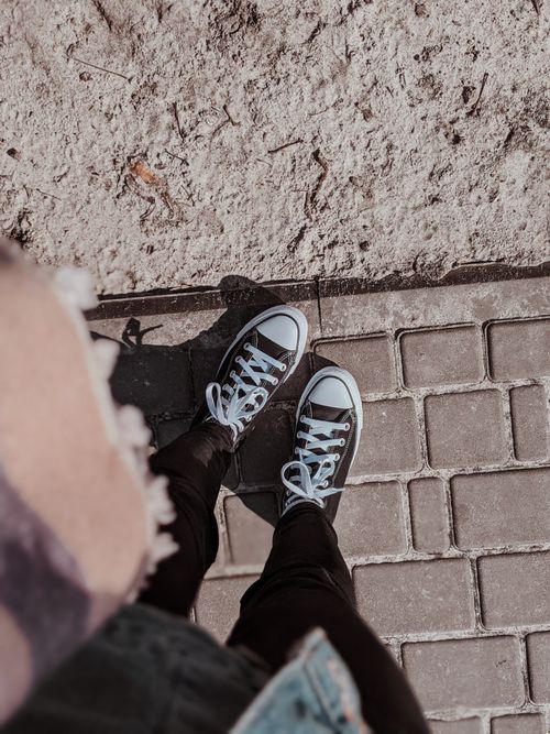 Free Top view of Converse sneakers on a paved path with a sandy texture background, showcasing casual fashion. Stock Photo