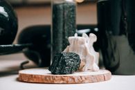 Wooden round shaped board with textured black stone on blurred background of magic interior