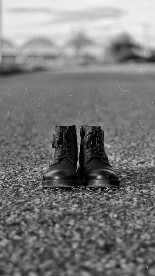 Free Black and white of leather shoes with tied laces placed on asphalt road in street on daytime Stock Photo