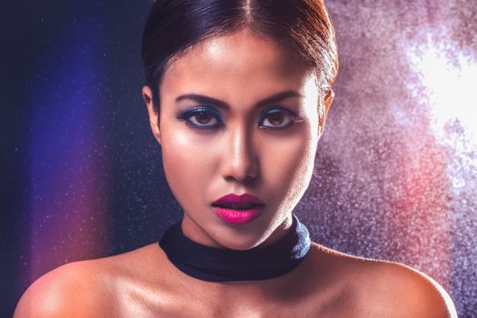 Captivating portrait of a woman with striking makeup and bold lighting.