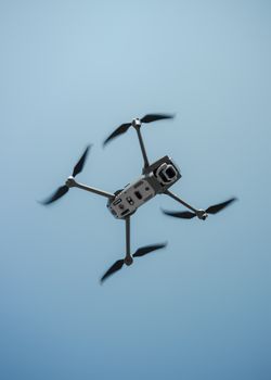 A high-definition capture of a drone flying against a clear blue sky.