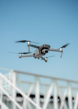 A sleek drone in flight with a clear blue sky background, showcasing modern technology.