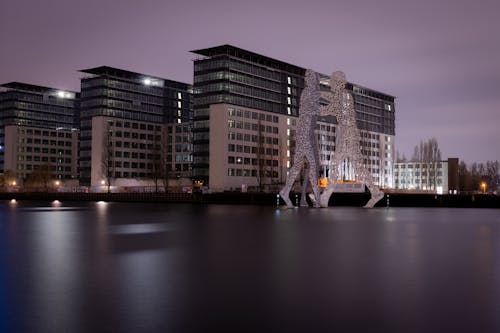 Aluminum Sculpture Molecule Man on the Spree River in Berlin at Dusk