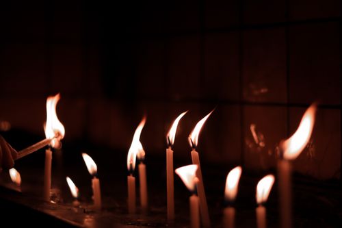 Free A serene image of candles burning brightly, casting a warm glow in a dimly lit space. Stock Photo