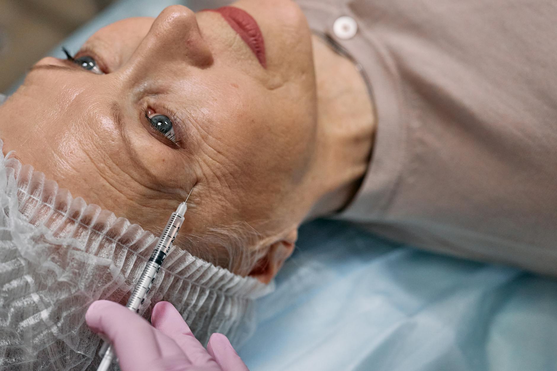 A senior woman undergoes a cosmetic injection procedure in a medical facility.