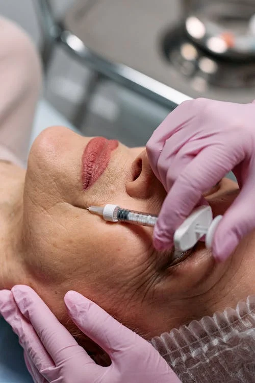 Hands Wearing Medical Gloves Injecting Syringe on Client's Face