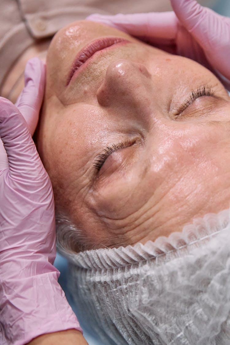 A Person Touching An Elderly Woman's Face