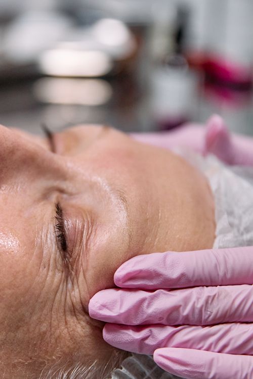 Free Close-up of a senior woman receiving a relaxing facial treatment in a spa setting. Stock Photo