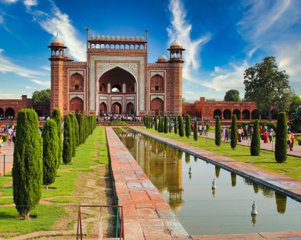 Majestic view of the main gate of Taj Mahal, showcasing Mughal architecture and vibrant gardens.