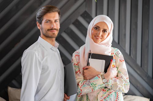 Free A Man Holding a Laptop and a Woman Holding a Notebook Stock Photo