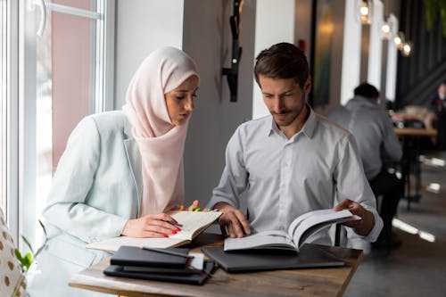 Free A Man Looking at a Brochure While a Woman Taking Notes Stock Photo