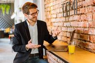 Man in Black Suit Jacket Sitting Beside Brown Wooden Table