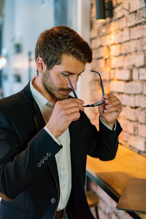 Free Man in Black Suit Holding Black Framed Eyeglasses Stock Photo
