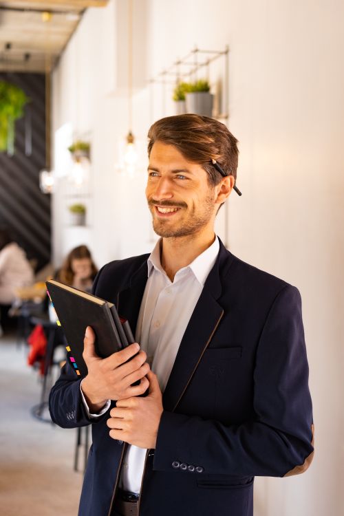 Free Smiling businessman in a suit holding notebooks in a modern office. Stock Photo