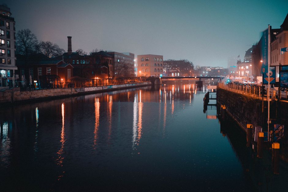Stunning nighttime view of a Berlin canal reflecting city lights and buildings.