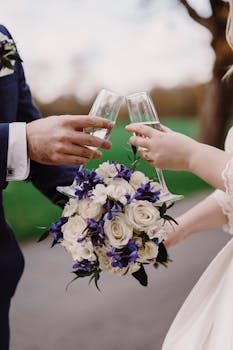 Couple toasting with wine glasses at an outdoor wedding with a beautiful flower bouquet.
