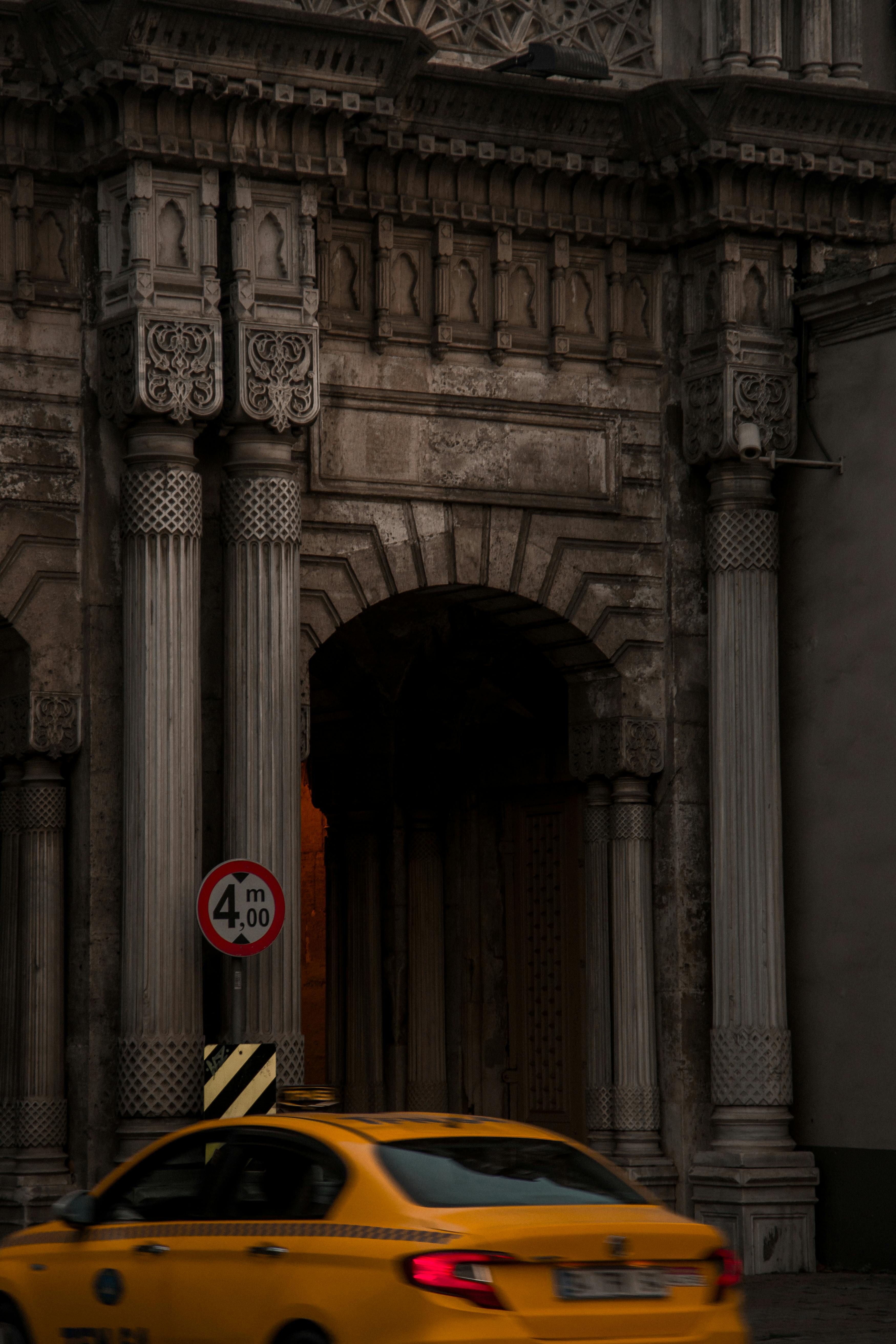 A yellow taxi passes by ornate historic architecture in Istanbul.