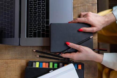 Person Holding Black Pencil and Notebook 