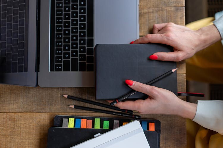 Person Holding Black Pencil And Notebook 