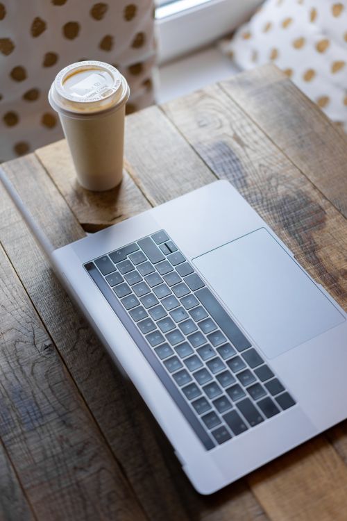 Free A minimalist workspace featuring a laptop and a coffee cup on a wooden table. Stock Photo