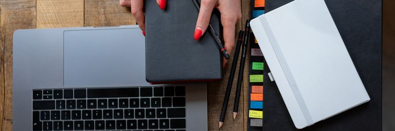 Top-down view of a desk with laptop, planner, and notebooks. Perfect for business and productivity themes.