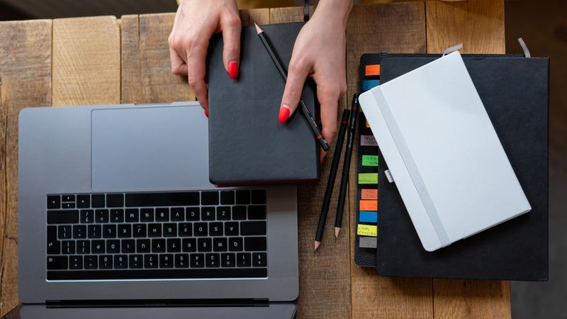 Top-down view of a desk with laptop, planner, and notebooks. Perfect for business and productivity themes.