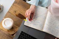 Person Holding Yellow Paper on Brown Wooden Table