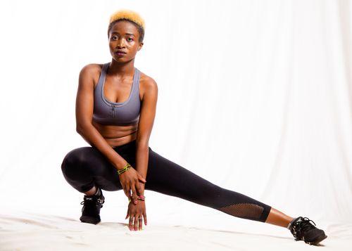 Free African woman performing a stretch in activewear, showcasing fitness and strength. Stock Photo