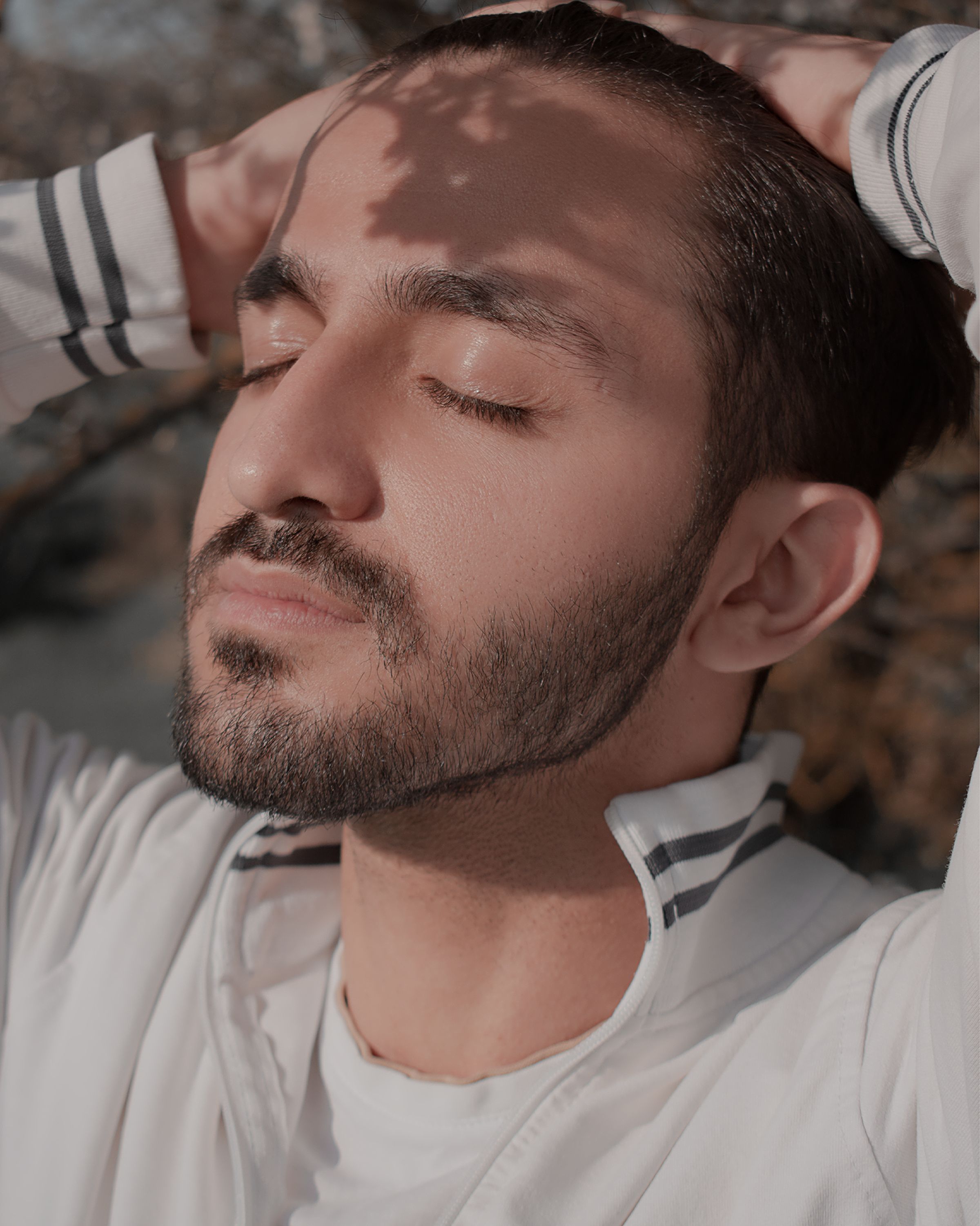 A serene close-up of a man with closed eyes enjoying the summer sunlight.