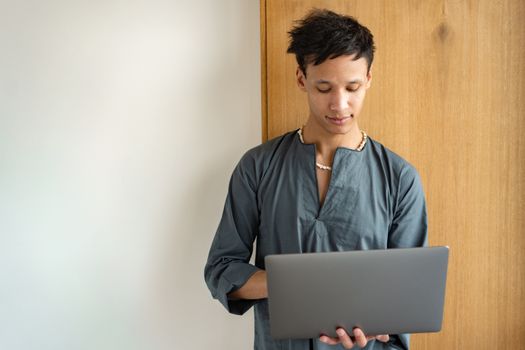 A young man smiling and working remotely on a laptop, embodying modern lifestyle and technology.