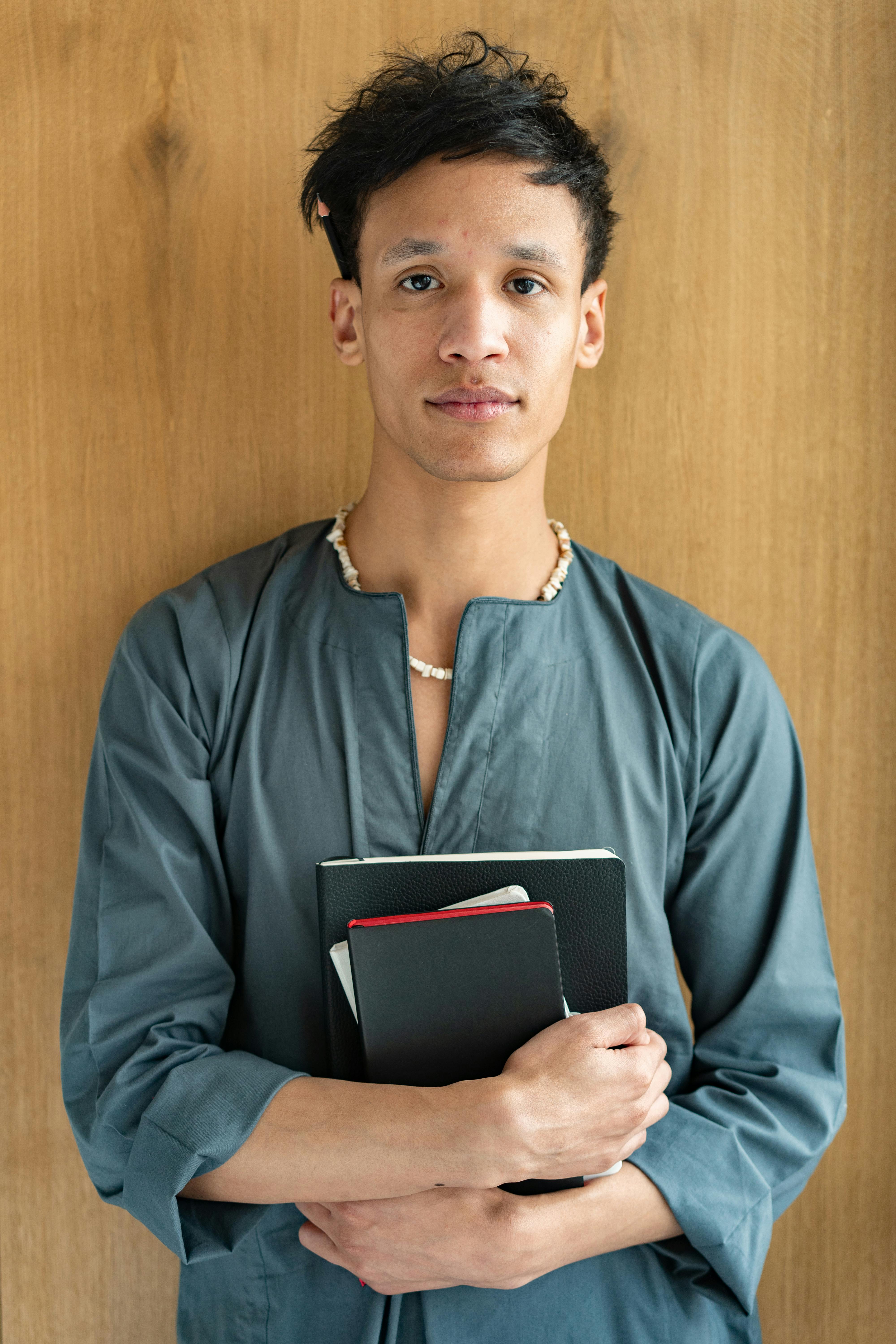 man in blue long sleeve shirt holding black notebooks