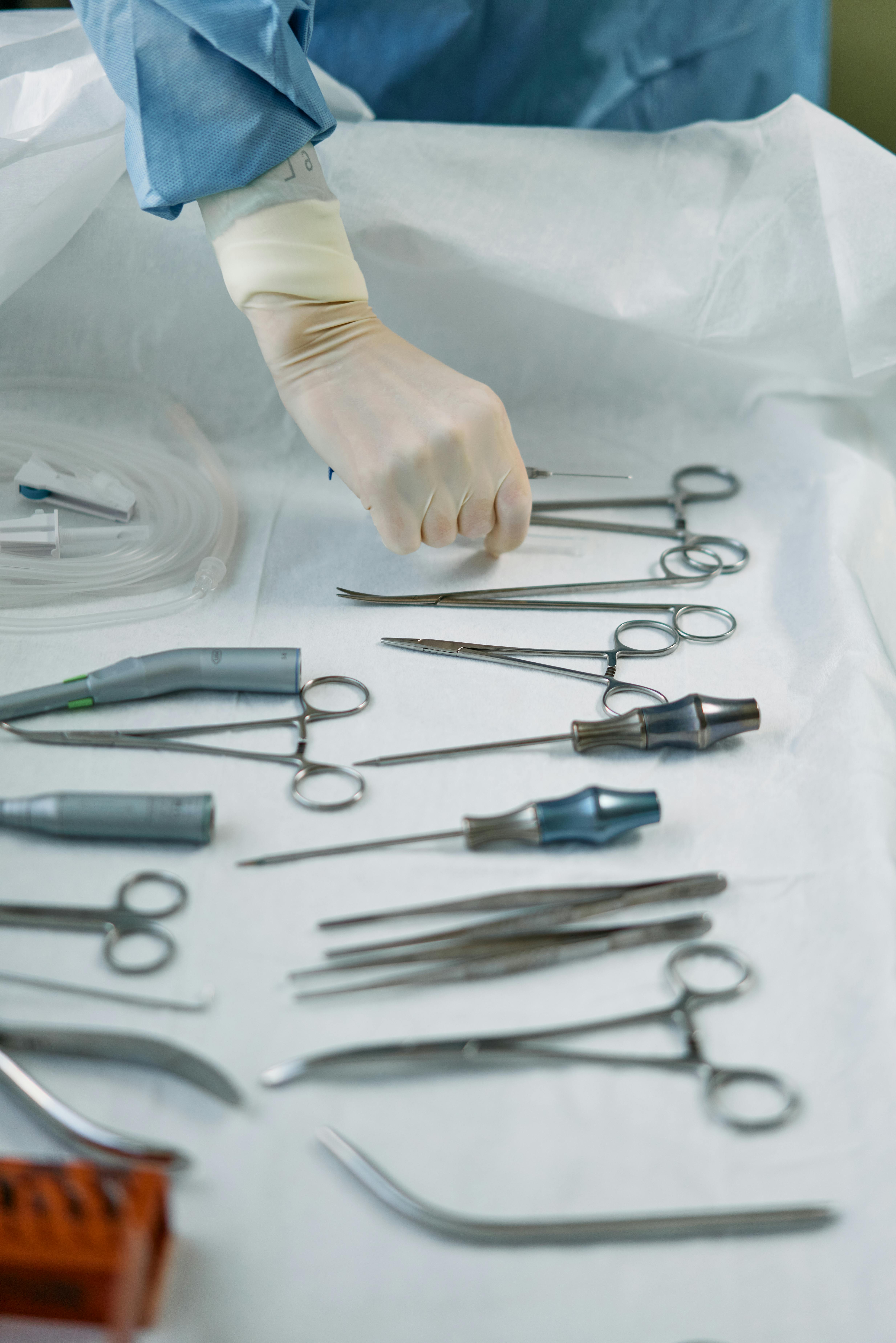 a person wearing white gloves holding a medical tool