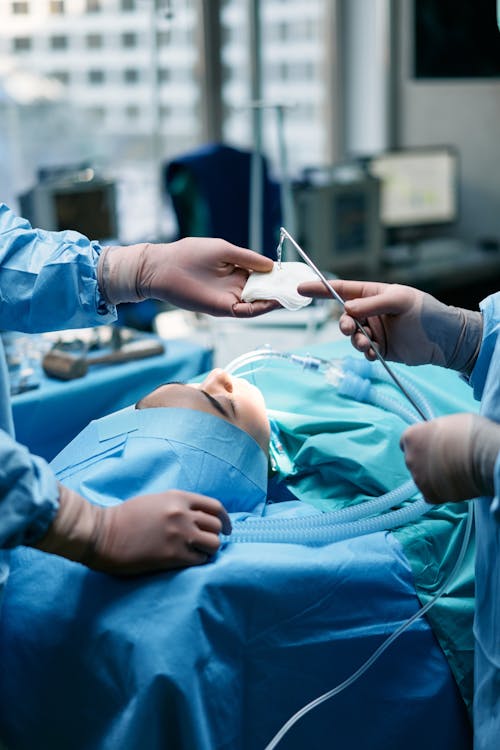 Person in Blue Scrub Suit Holding White Plastic Tool