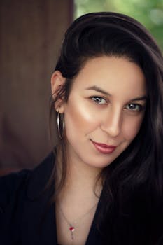 Close-up portrait of a smiling woman with long dark hair and hoop earring.