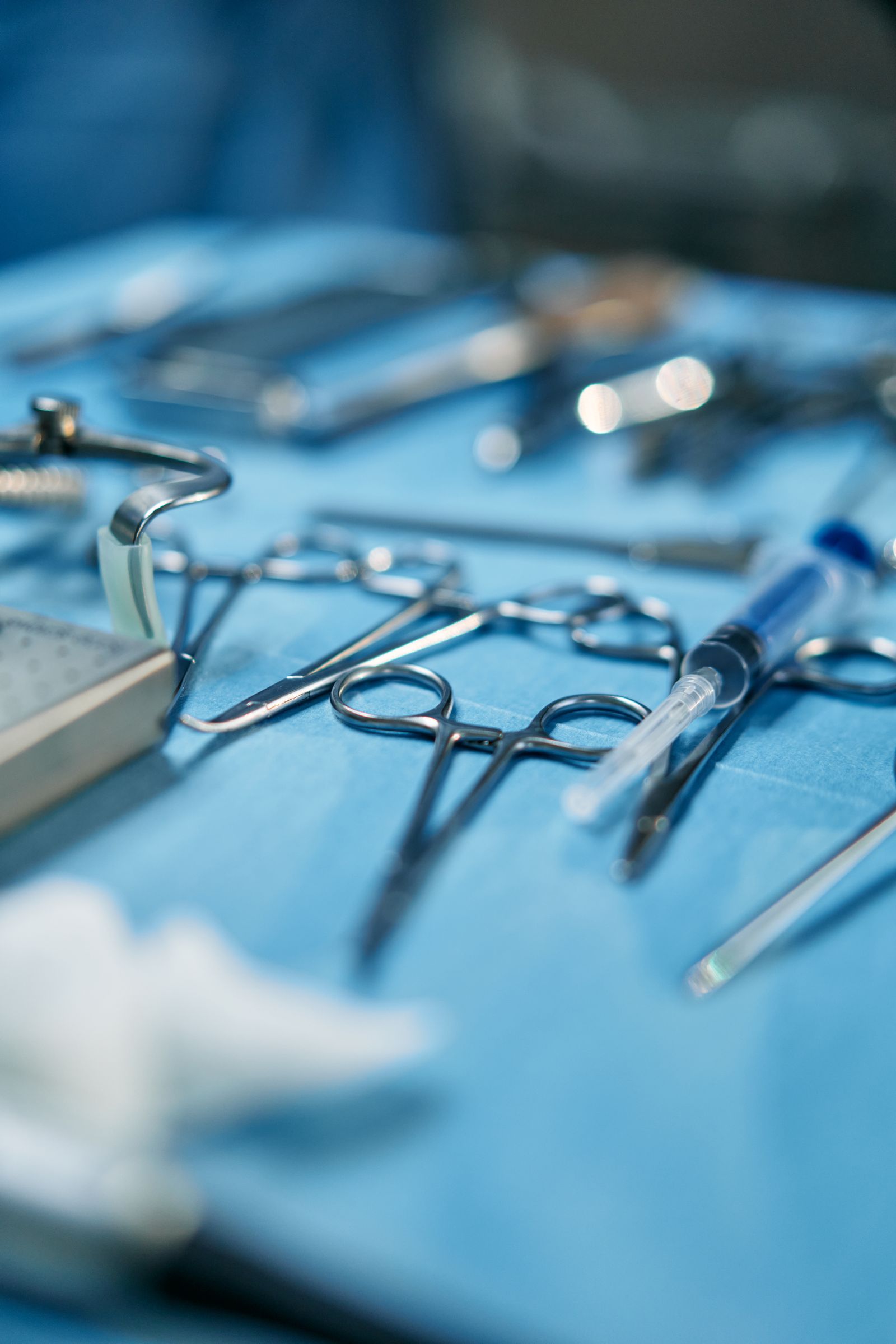 Stainless steel surgical scissors and instruments on a sterile blue cloth, inspected for quality