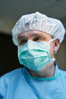 Portrait of a surgeon in scrubs with a face mask, focused during an operation.