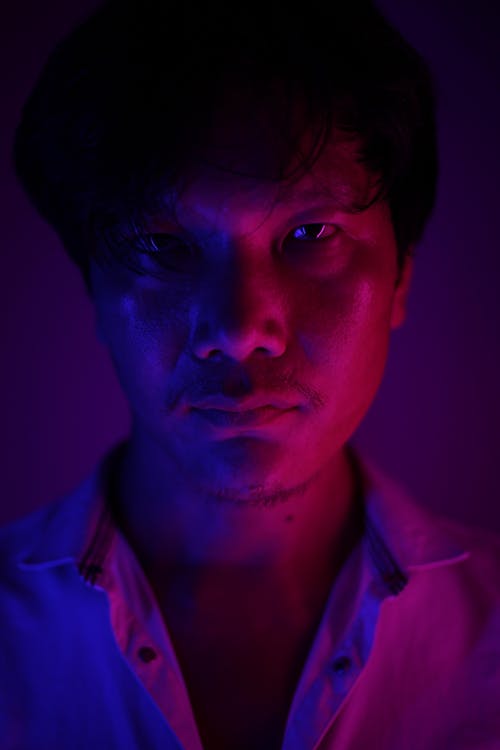 Emotionless Asian man in ultraviolet light