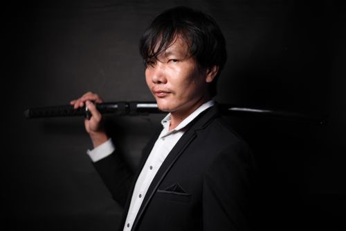 Free Brutal ethnic male with dark short hair and sharp heavy katana in black formal jacket in studio Stock Photo