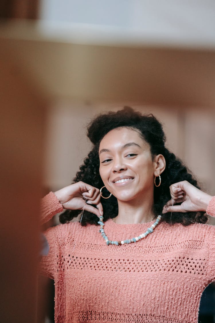 Smiling African American Woman Putting On Necklace