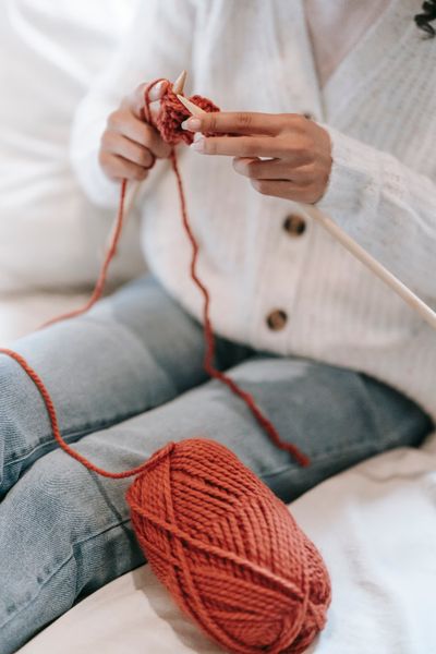 Hands mid-row with terracotta yarn on the needles — Miriam Alonso on Pexels