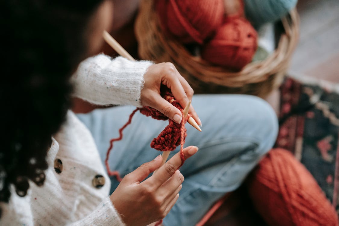 Unrecognizable woman knitting with threads