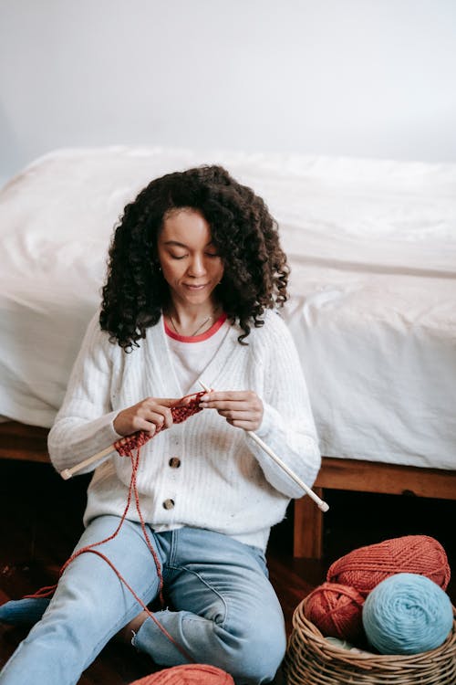 Focused African American woman knitting with red threads
