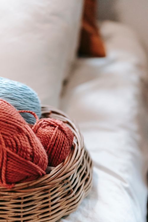 Free From above of whisker basket with colorful wool yarns placed on soft bed in daylight Stock Photo