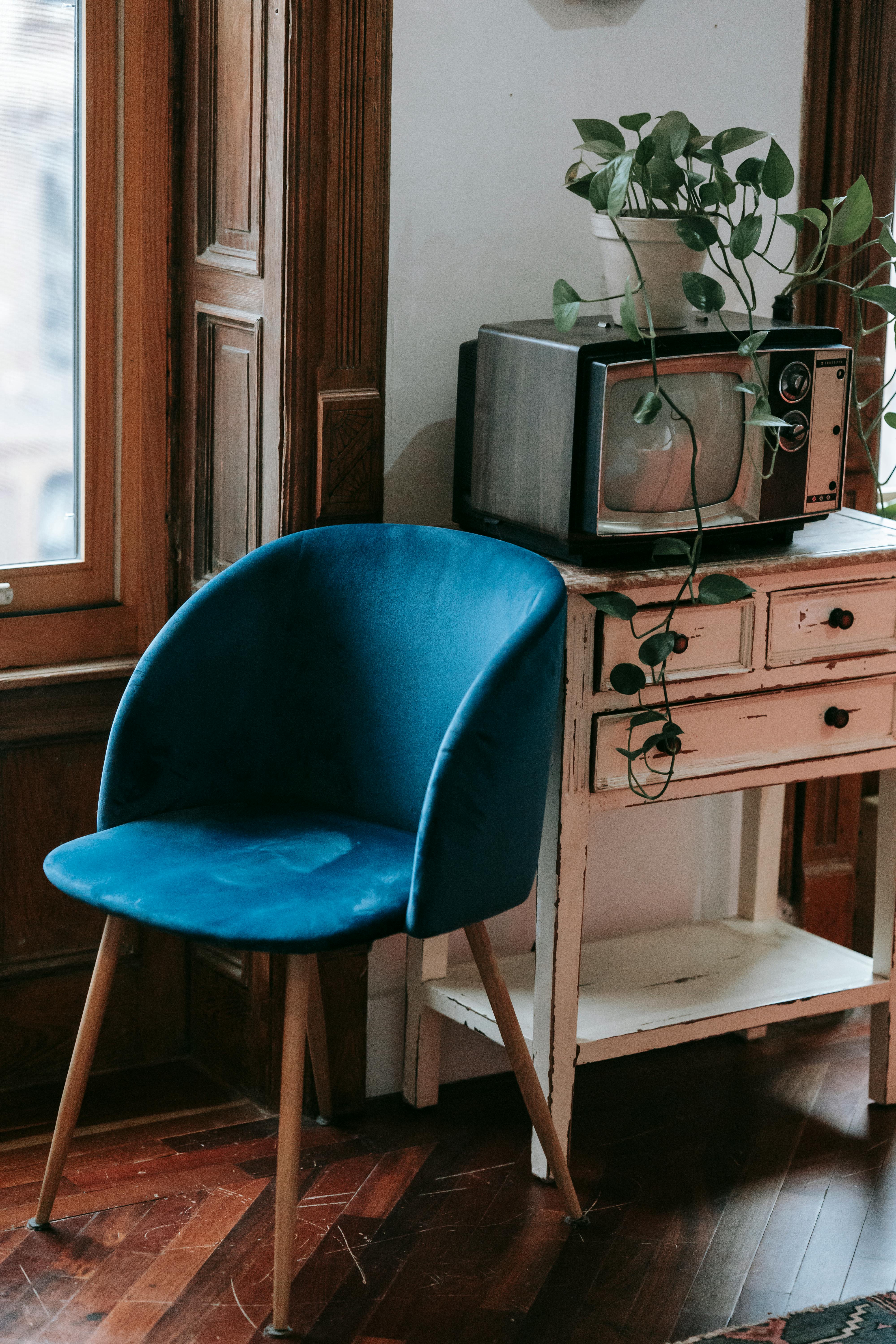cozy chair placed near shabby cabinet with retro tv