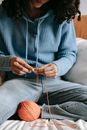 A Woman in Knitted Sweater Sitting while Crocheting