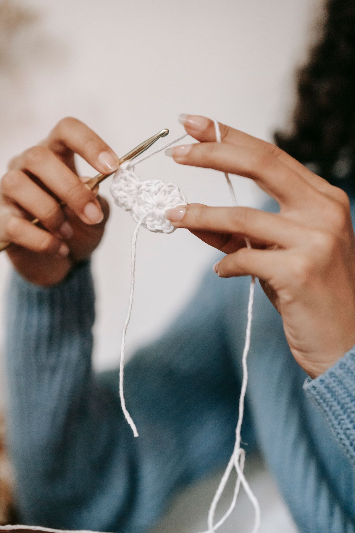 Detailed view of a person crocheting with white yarn, highlighting craftsmanship and detail.