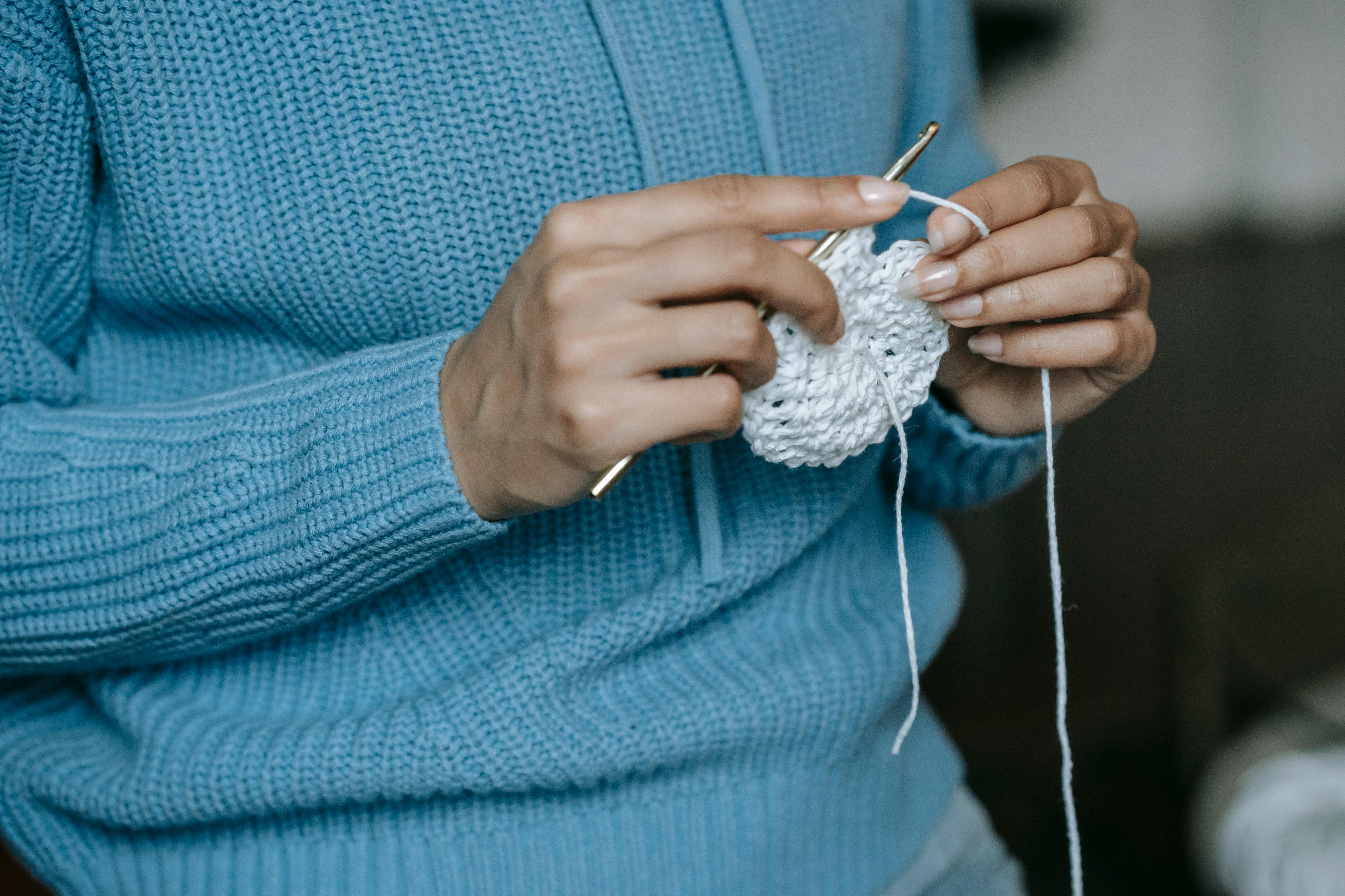 A person skillfully crochets a white yarn piece, showcasing the art of handmade craft.