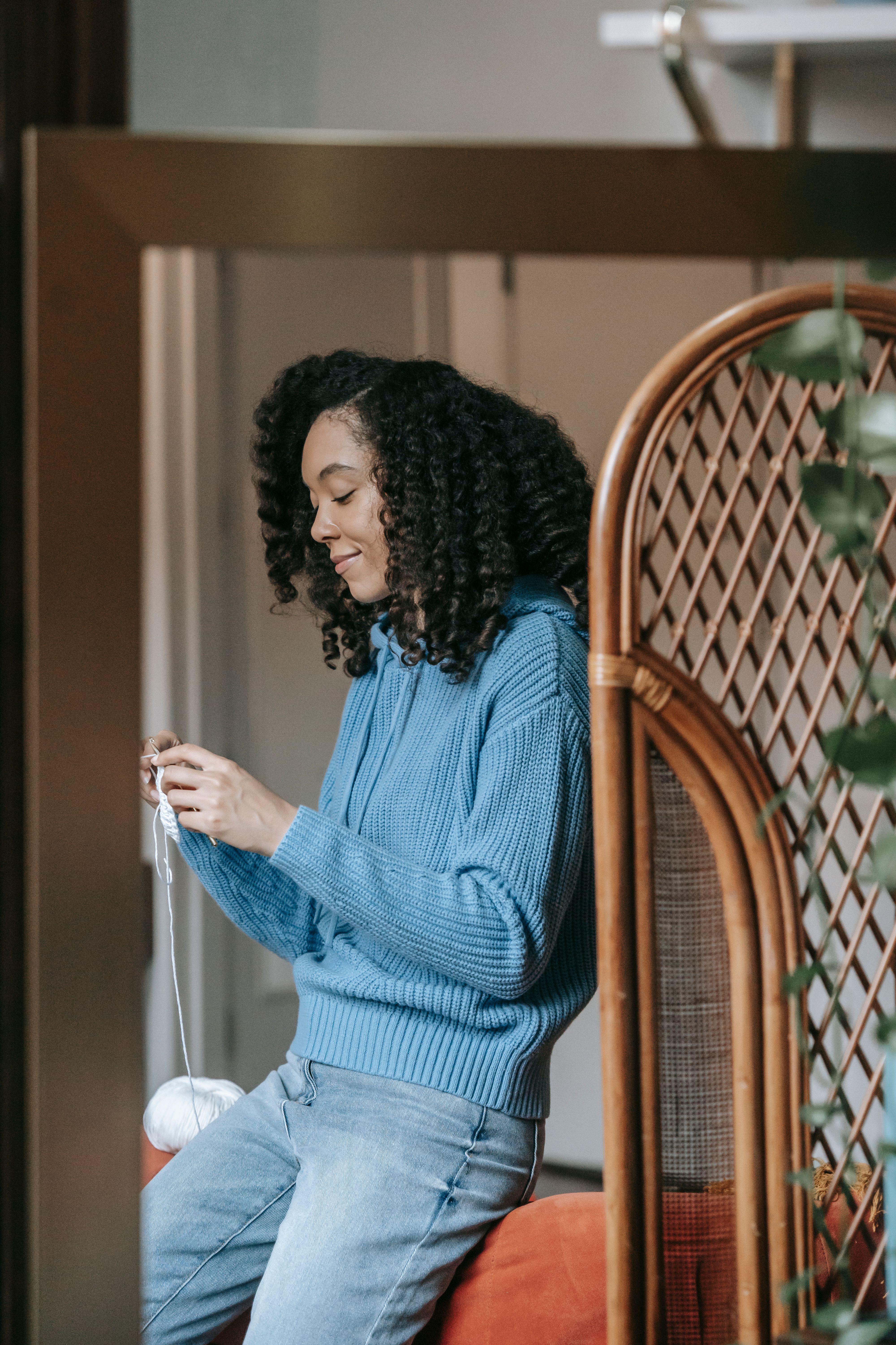 A Woman in Knitted Sweater Sitting while Holding a Yarn · Free Stock Photo